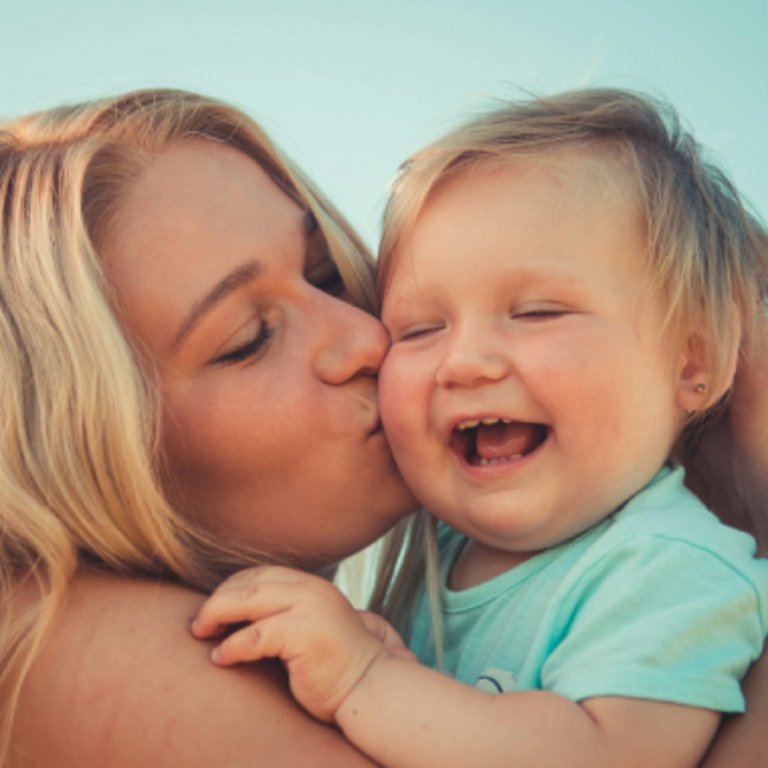 Une mère embrasse la joue de son bébé