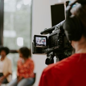 Une personne tient une caméra, elle filme deux personnes en arrière-plan