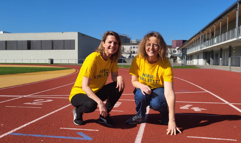 Spendenlauf in Rotkreuz Zwei Frauen mit gelben FRAGILE-T-Shirts kauern auf der Laufbahn.